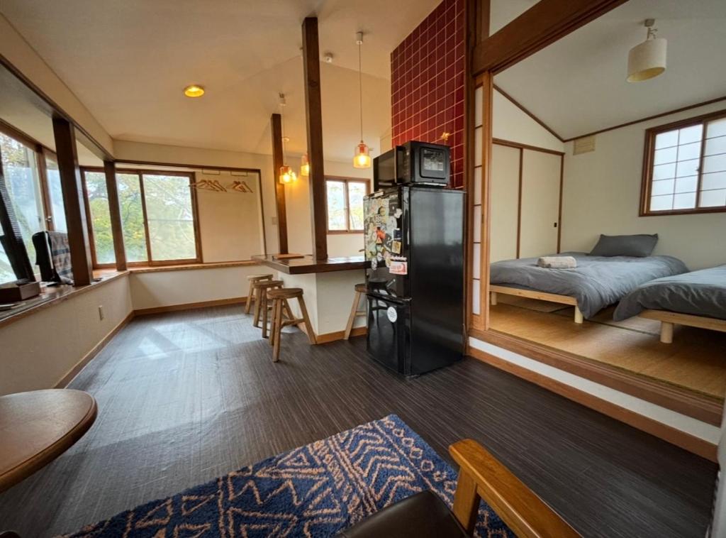 een kamer met een koelkast en een slaapkamer met een bed bij tiny tiny Niseko in Niseko