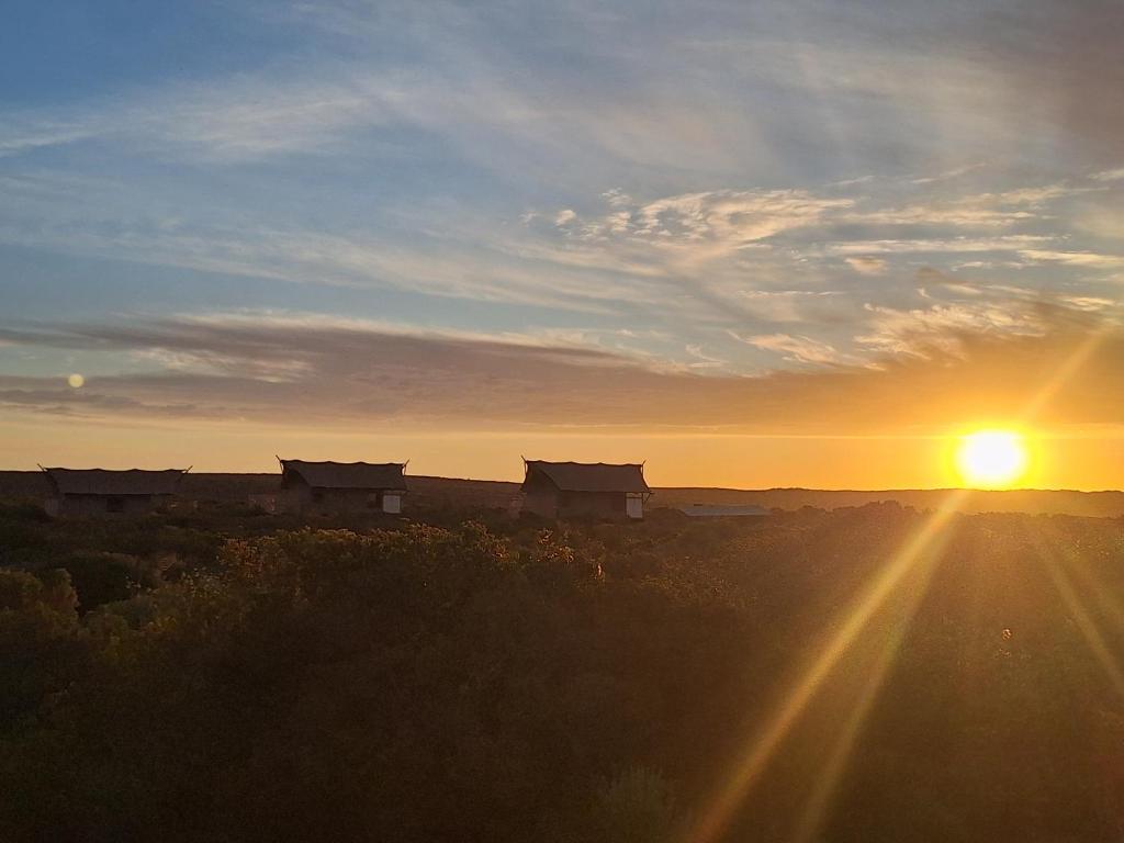 a sunset with a group of houses in the distance at Trekosglamping luxury tents 