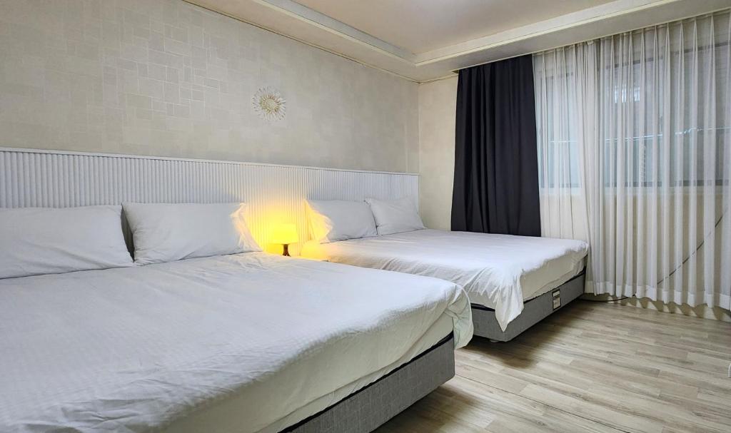 ein Hotelzimmer mit zwei Betten und einer Lampe in der Unterkunft 대게, Private Kintex Daehwadong in Goyang
