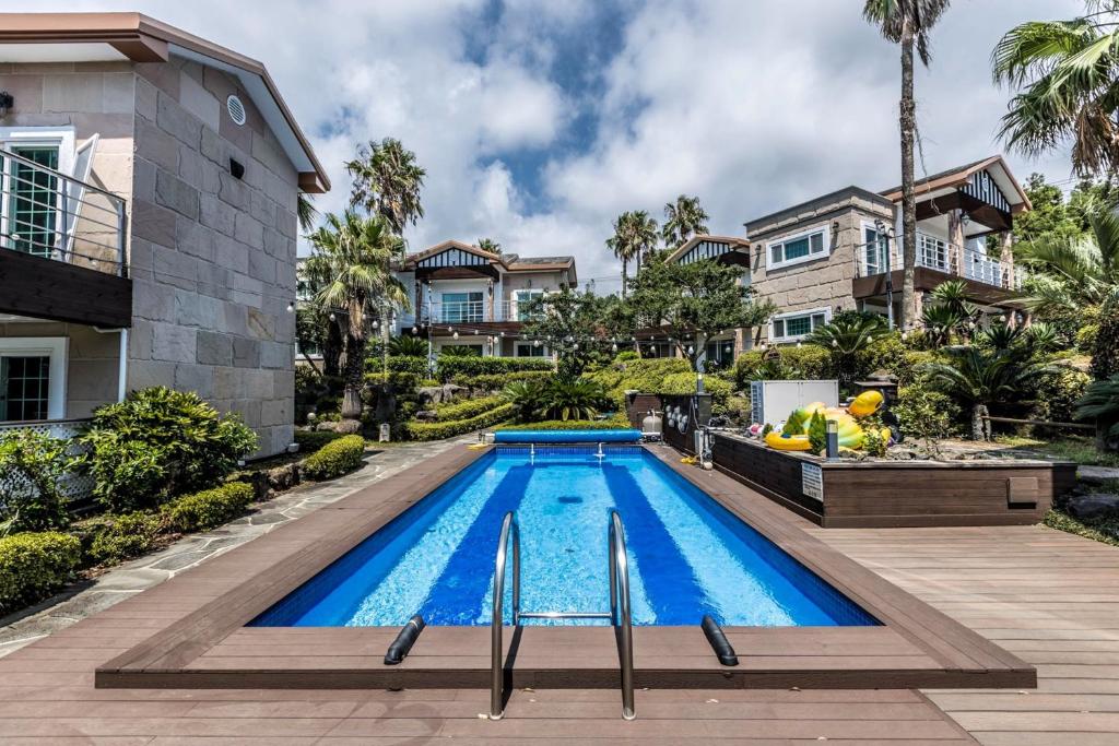 a swimming pool in front of a house at Monaco Pool Pension in Seogwipo