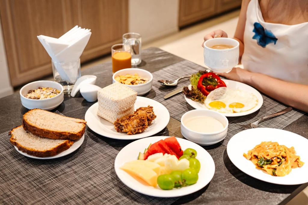 A generously styled breakfast table with eggs, toast, fruit, noodles, cereal and hot drinks.