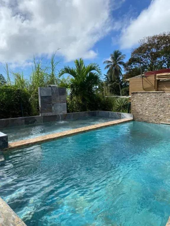 a swimming pool with blue water at Appartement avec piscine à Capesterre-Belle-Eau in Capesterre-Belle-Eau