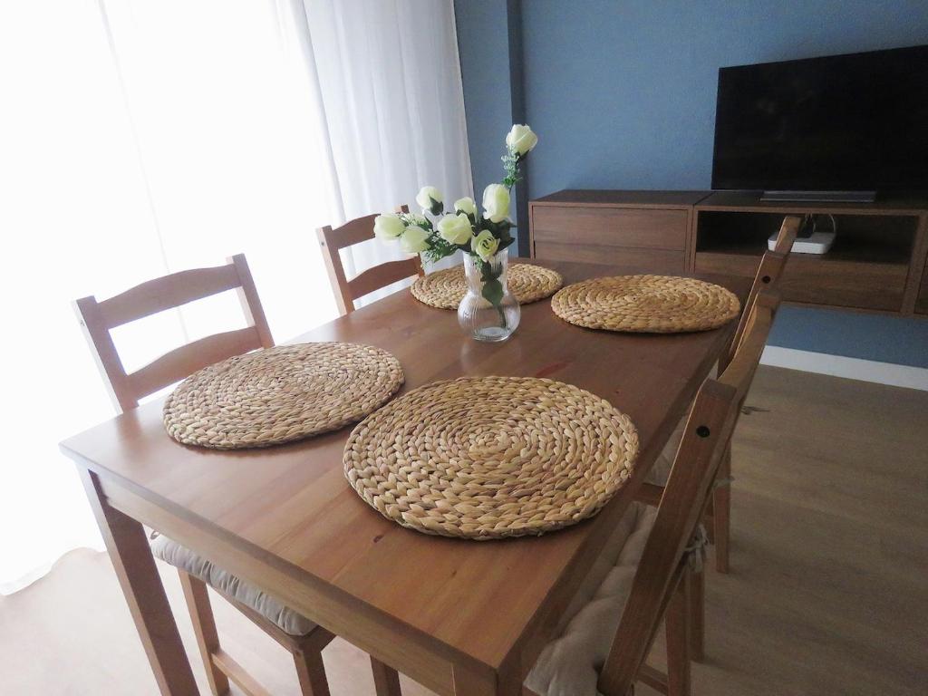 une table en bois avec quatre chaises et un vase de fleurs dans l'établissement La Casina Poniente,cerca de la playa, à Gijón