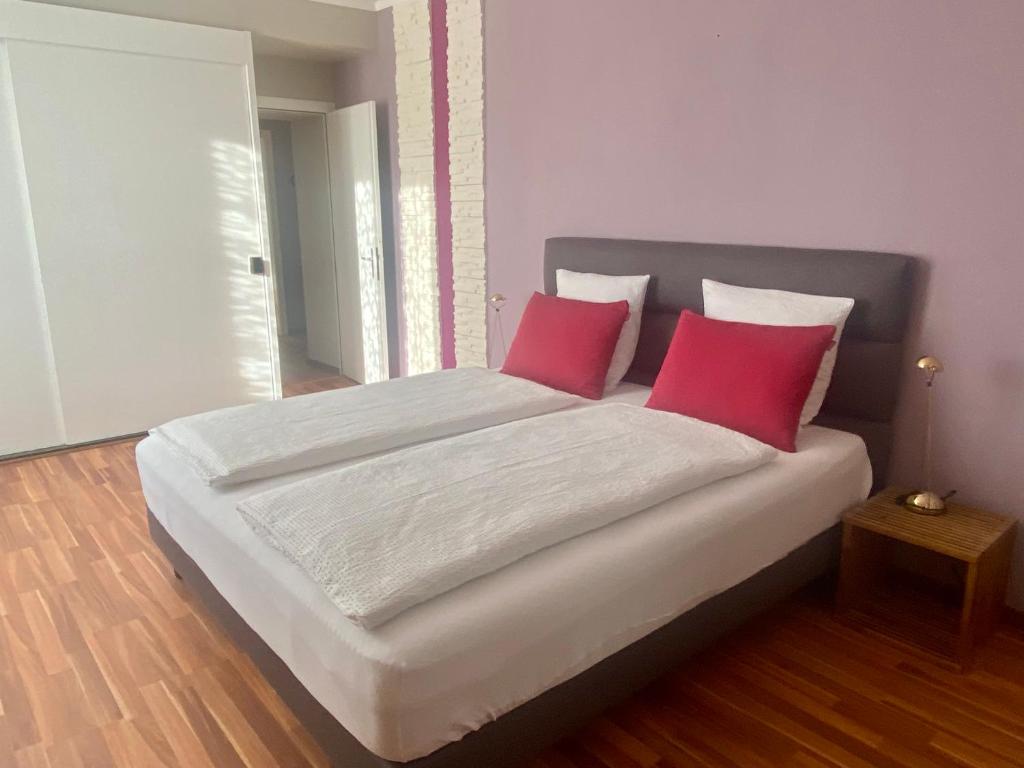 a bedroom with a large bed with two red pillows at Hôtel de la Gare in Saignelégier