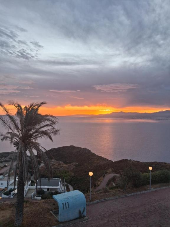 a sunset over the ocean with a palm tree at Theseus beach with sea and sunrise view in Heraklio Town