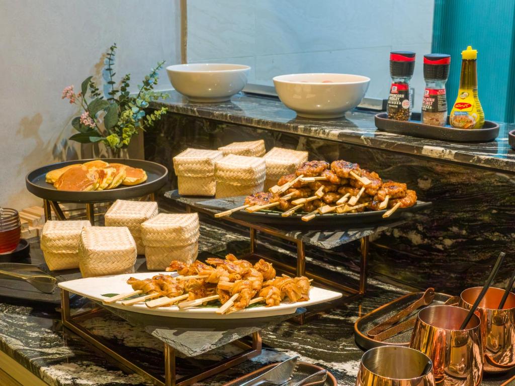 A buffet station displaying skewers, fried items, condiments and bread in serving dishes.