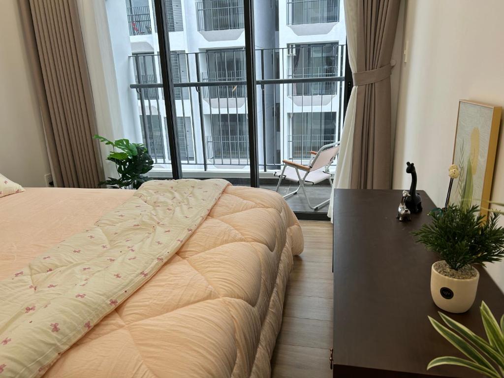 a bedroom with a bed with a table and a large window at Nghỉ dưỡng MT Eastmark in Xóm Ðội Bảy Ti