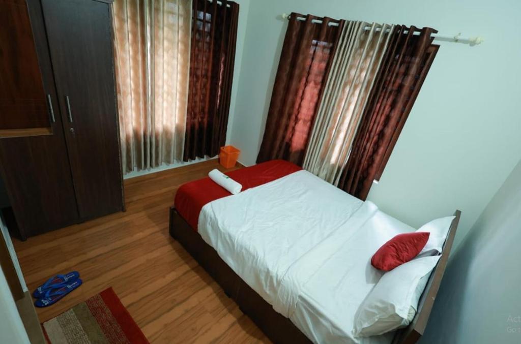 a small bedroom with a bed with red pillows at Prakrithi Luxe Retreat in Padinjarathara