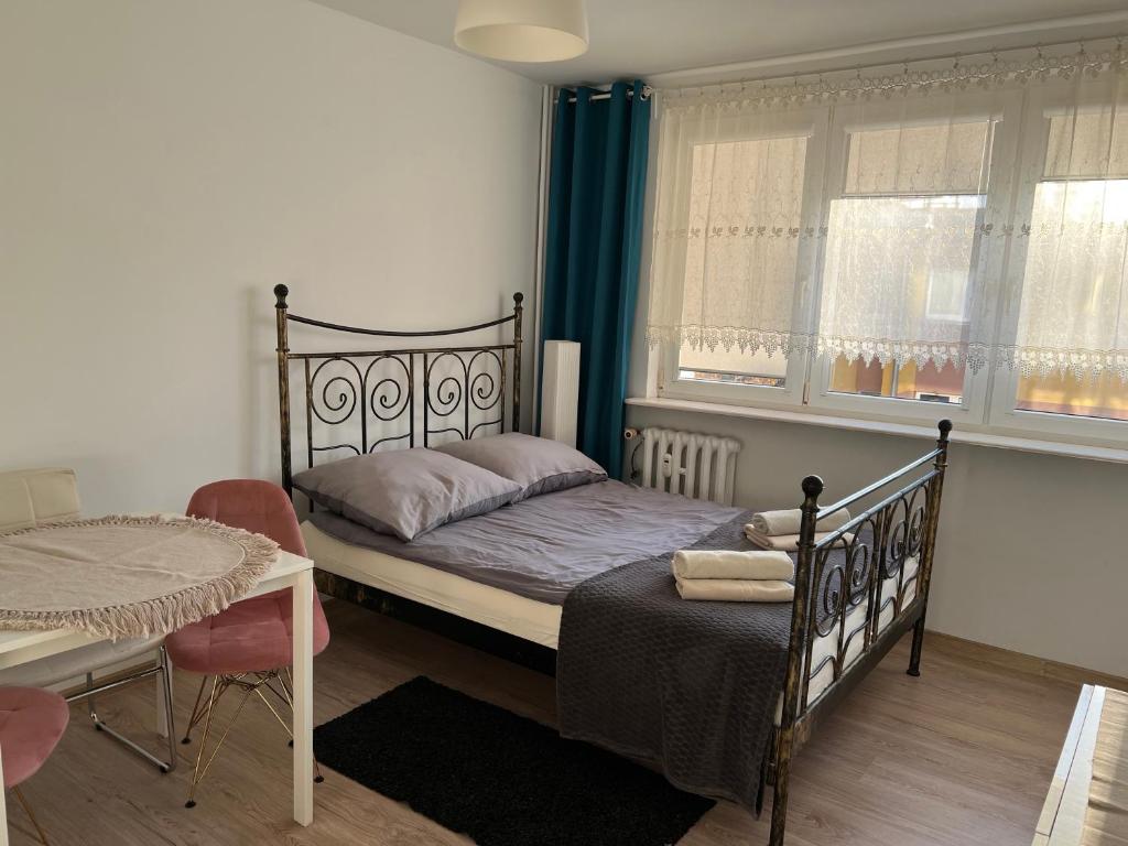 a bedroom with a bed and a table and a window at Apartament Przytulny przy plaży in Sopot