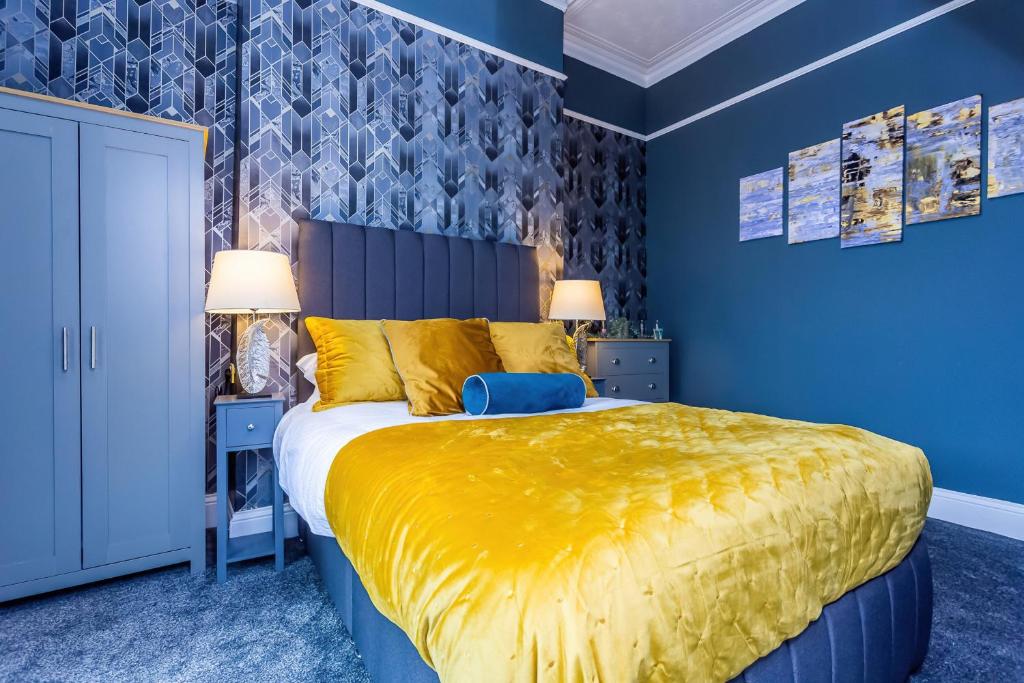 a blue bedroom with a large bed with a yellow bedspread at Room 01 - Sandhaven Rooms - Double in South Shields