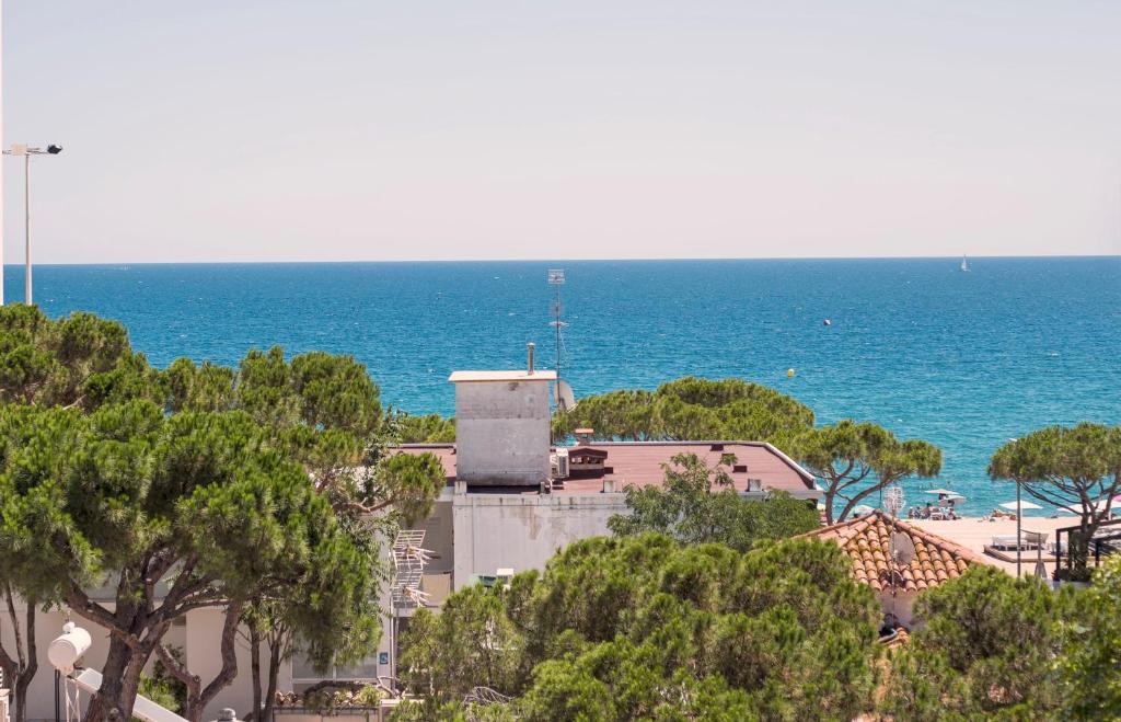 een uitzicht op de oceaan met een gebouw en bomen bij Hotel Medium Claramar in Platja  d'Aro