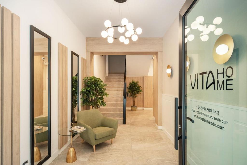 a hallway with a green chair and a glass door at Vita Home Lanzarote I Deluxe Apartments in Arrecife