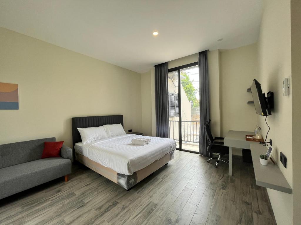 a bedroom with a bed and a couch and a television at Cove Legacy in Jakarta