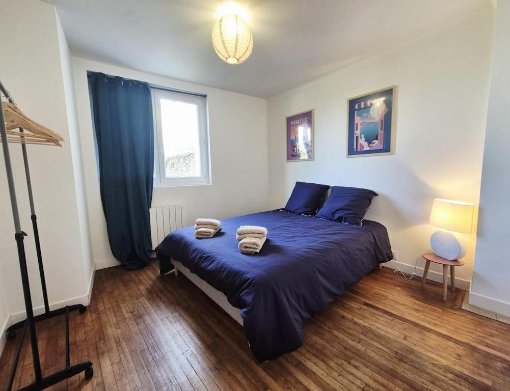 Un dormitorio con una cama con sábanas azules y una ventana. en Parenthèse à l'Oasis, en Ploërmel