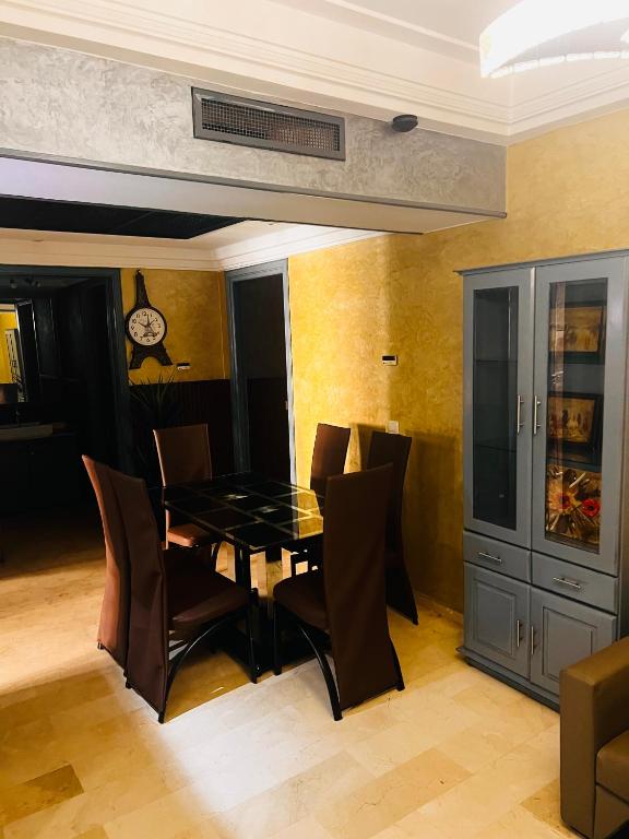 uma sala de jantar com mesa e cadeiras e um relógio em Corniche Apartments em Casablanca