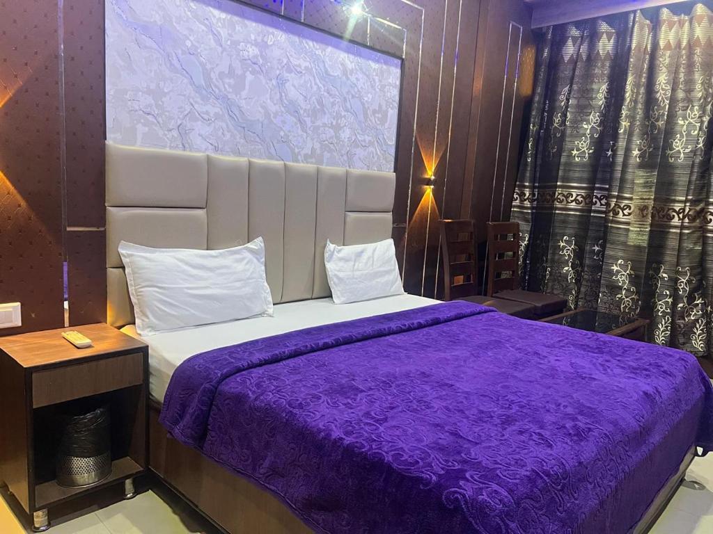 Un dormitorio con una cama con una manta morada. en Blessing Inn Hotel, en Jalandhar