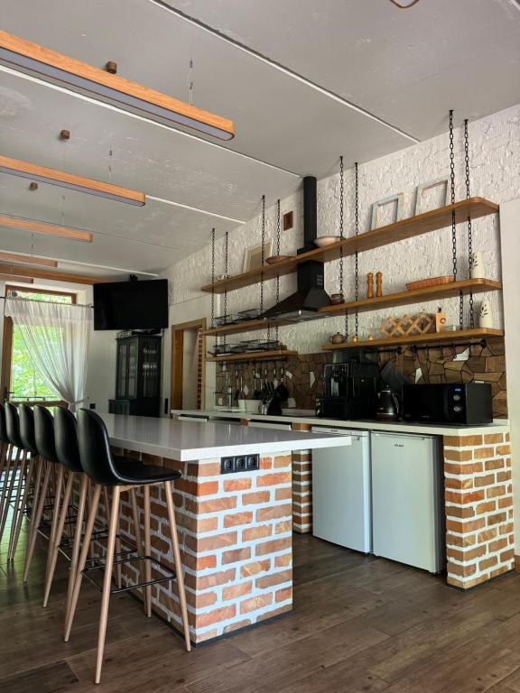 a kitchen with a bar with chairs and a brick wall at кемпінг-парк Метеорит in Orlovshchina