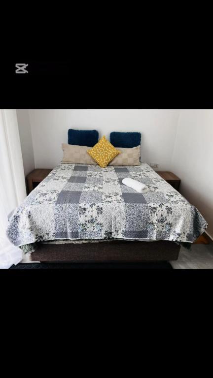 a bed with a blue and white blanket and pillows at Shalom Apartment in Lusaka