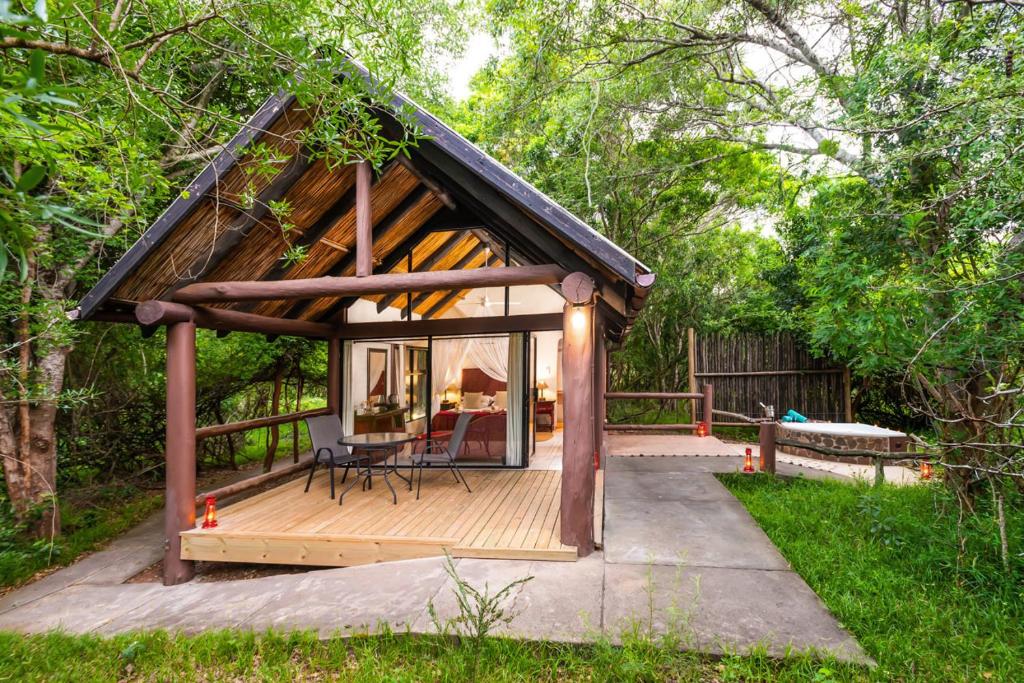 a small cabin with a deck in the woods at Lodge Forest Suite in Hluhluwe