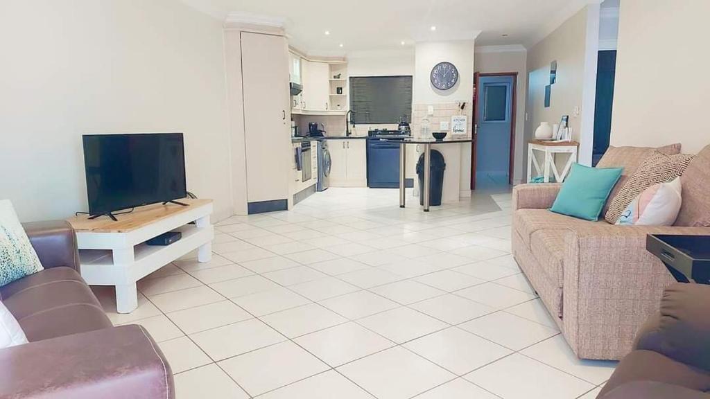 Una sala de estar con un sofá y un televisor de pantalla plana. en Perfect holiday destination!, en Jeffreys Bay