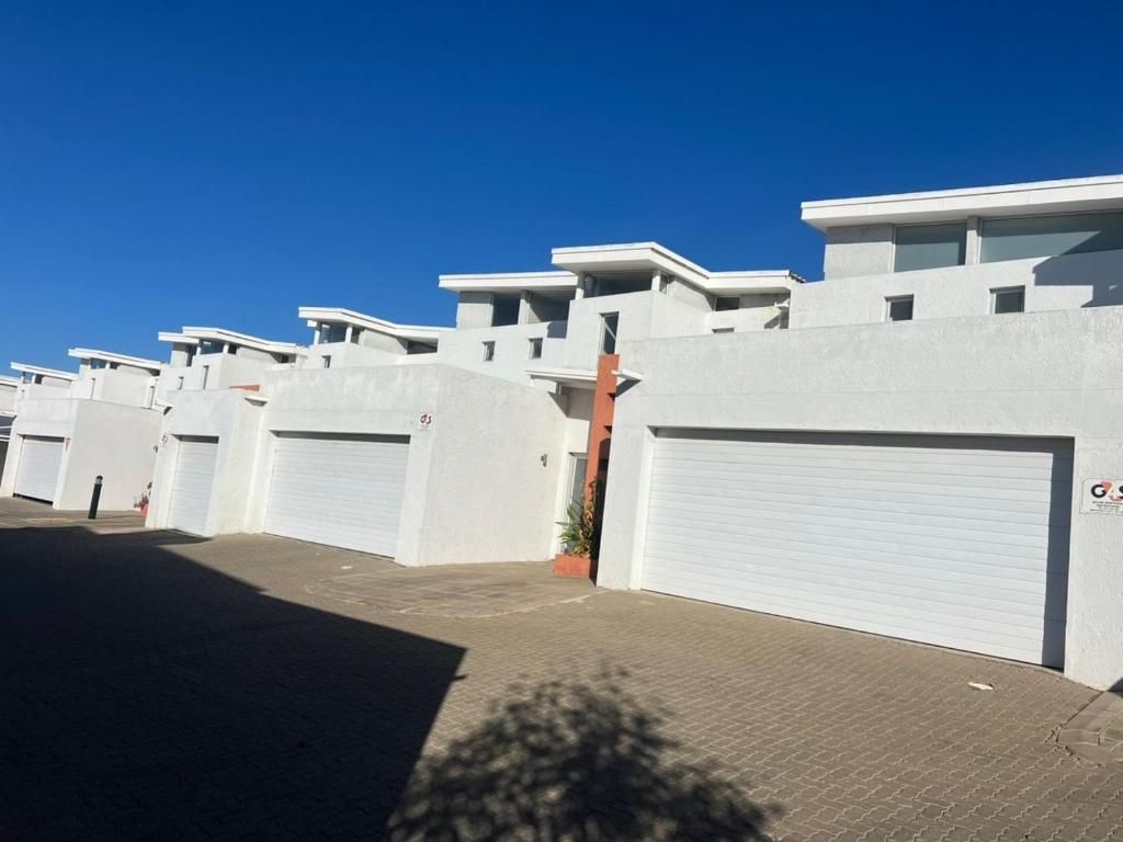 a white building with four garage doors on it at Haven Luxury Apartment in Windhoek