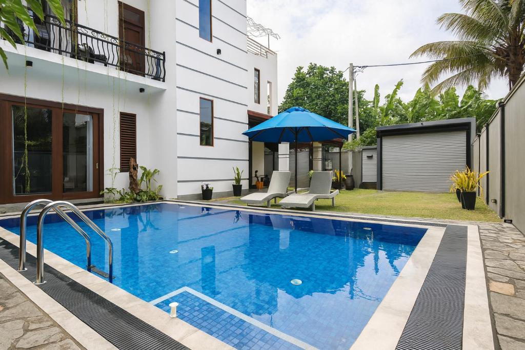 a swimming pool with an umbrella next to a building at Sapphire Escape - Private Villa in Ambalangoda in Ambalangoda