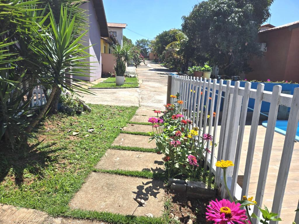 un jardin fleuri à côté d'une clôture blanche dans l'établissement Temporada Belas Casas, à São Pedro
