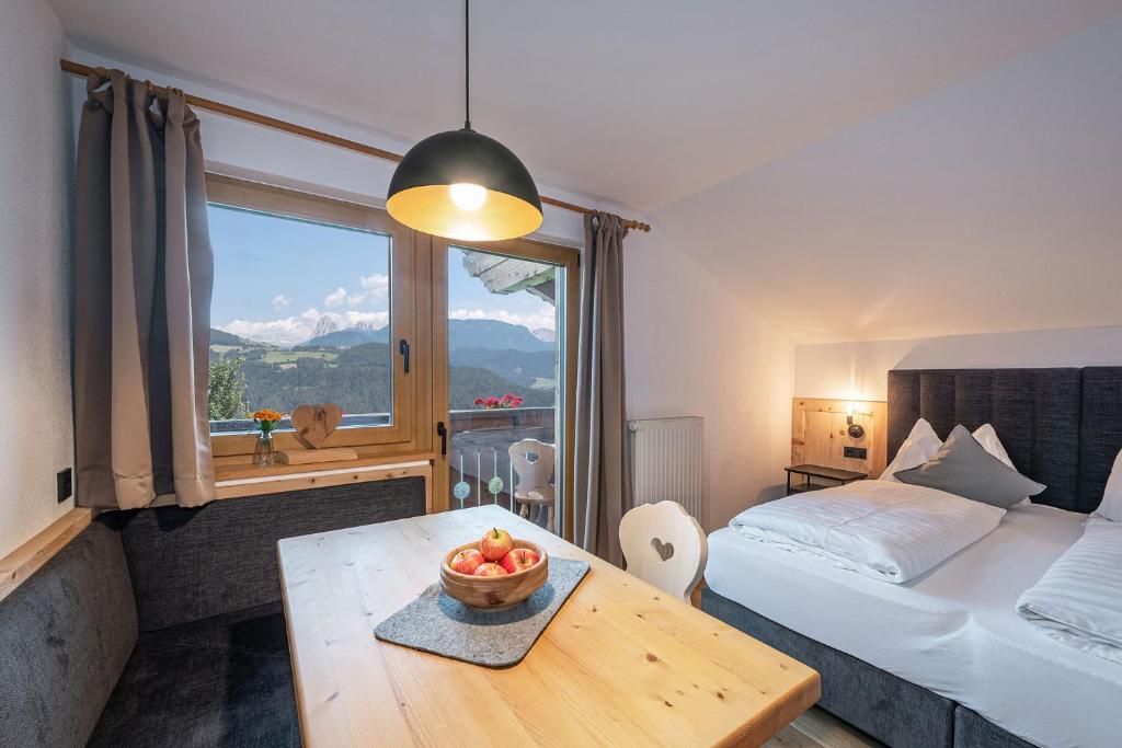 ein Schlafzimmer mit einem Bett und einem Tisch, auf dem eine Obstschale steht in der Unterkunft HAUSERHOF Farmhouse with Dolomite View in Villanders