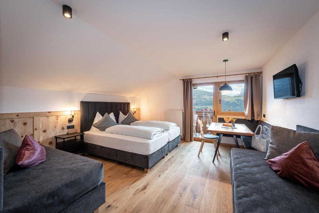 una habitación de hotel con una cama y un sofá en HAUSERHOF Farmhouse Escepe & Dolomite View, en Villandro
