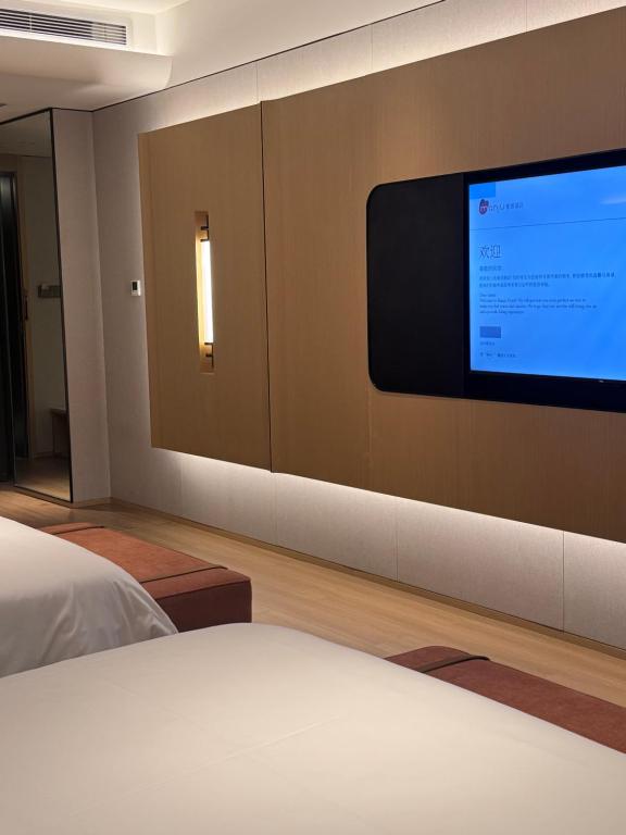 een slaapkamer met een flatscreen-tv aan de muur bij Manju Hotel Fuquan People's Square Branch in Fuquan