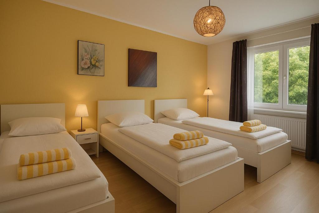 zwei Betten in einem Zimmer mit gelben Wänden in der Unterkunft VAJAGIC Apartment 2 mit GartenLounge! Messe, Klinikum, Krupp Krankenhaus in Essen