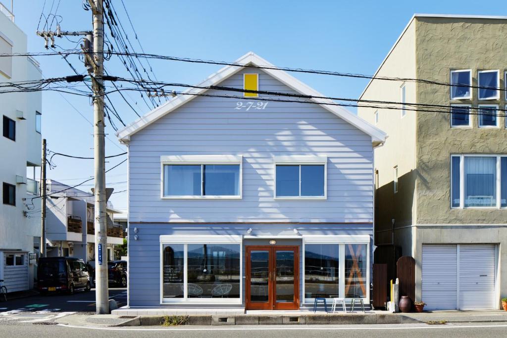 a blue house with a red door on a street at the lounge Kamakura HASE in Kamakura