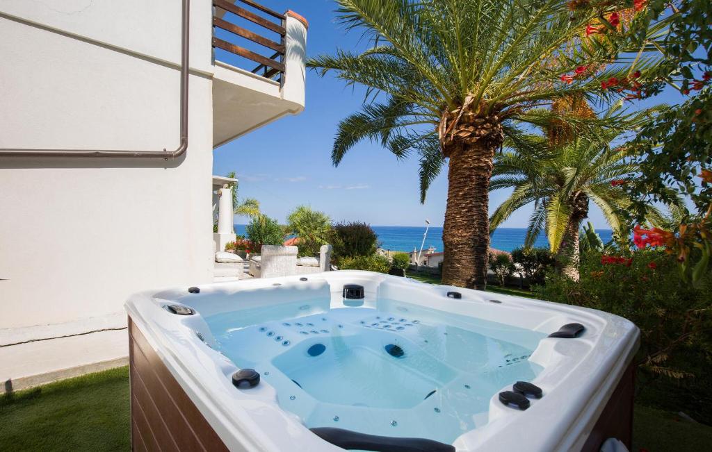 a jacuzzi tub in a yard with a palm tree at Villa Mare Panoramica Estia in Brancaleone Marina