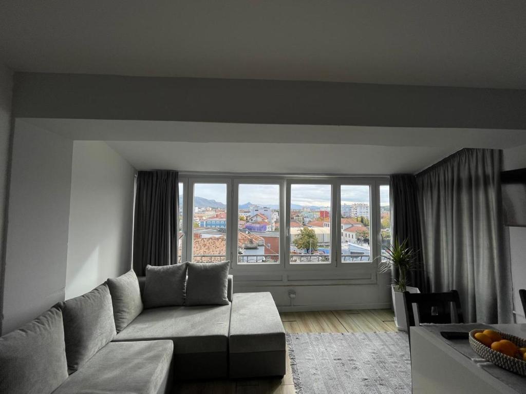 a living room with a couch and a large window at I&O Loft360 in Shkodër