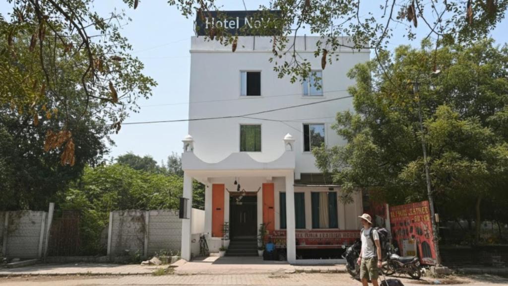 a man standing in front of a white building at Hotel Novo Agra in Agra
