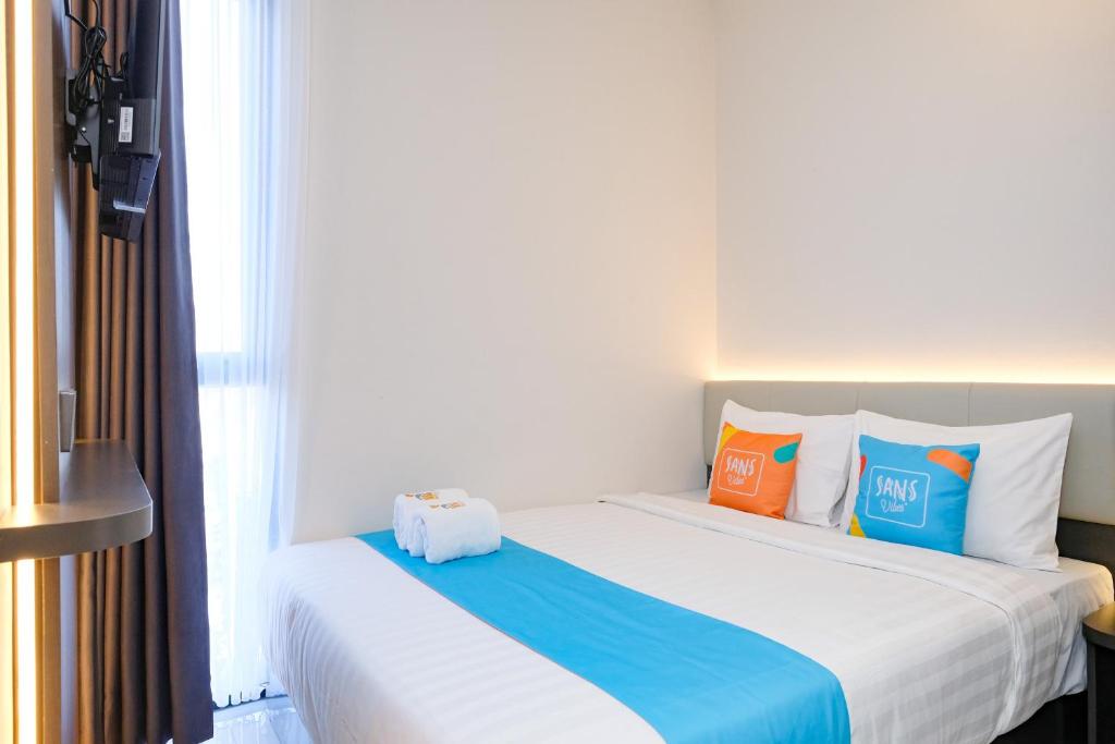 a hotel room with a bed with colorful pillows at Sans Vibes Hotel Damai Yogyakarta in Kejayan