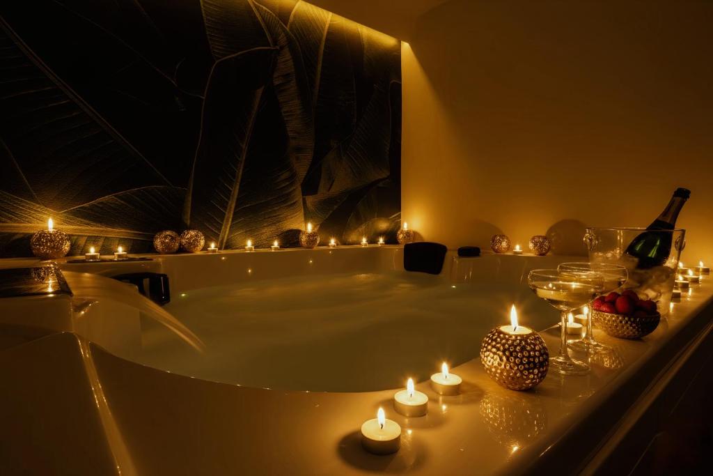 een badkamer met een bad met kaarsen en een fles wijn bij VillaNoa Luxury Stay in Cagliari