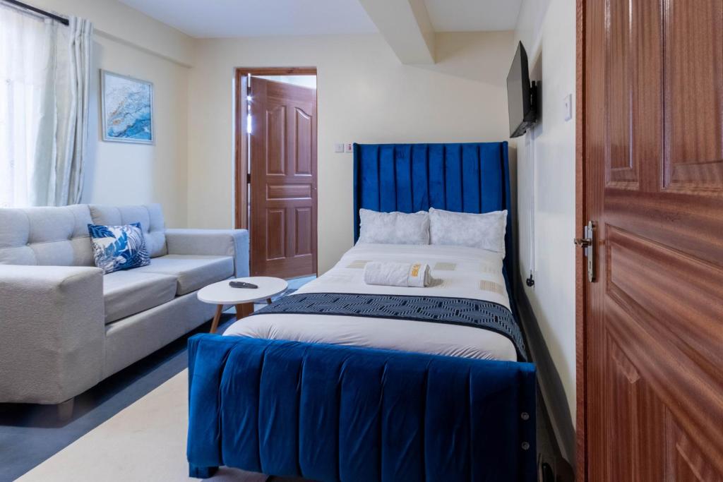 een slaapkamer met een blauw bed en een bank bij Cyan Studio with free WI-FI in Nanyuki