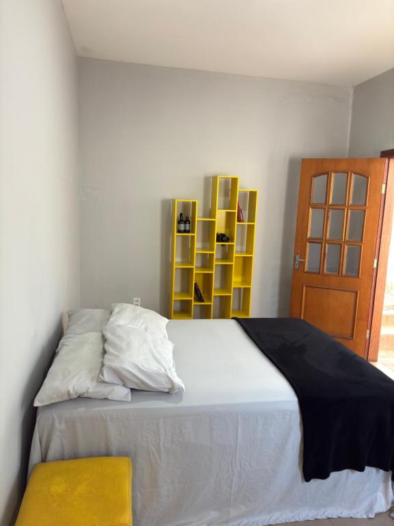 a bedroom with a large bed with a yellow chair at Suíte - Centro de Itu in Itu