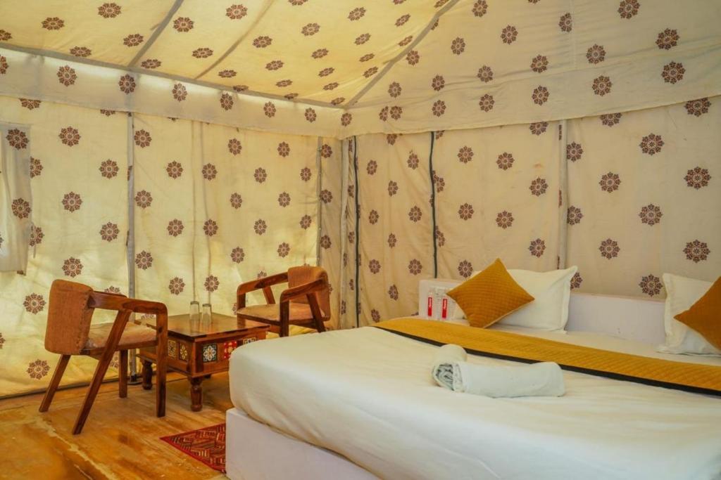 une chambre avec un lit, une table et des chaises dans l'établissement Desert Surprise Resort, à Jaisalmer