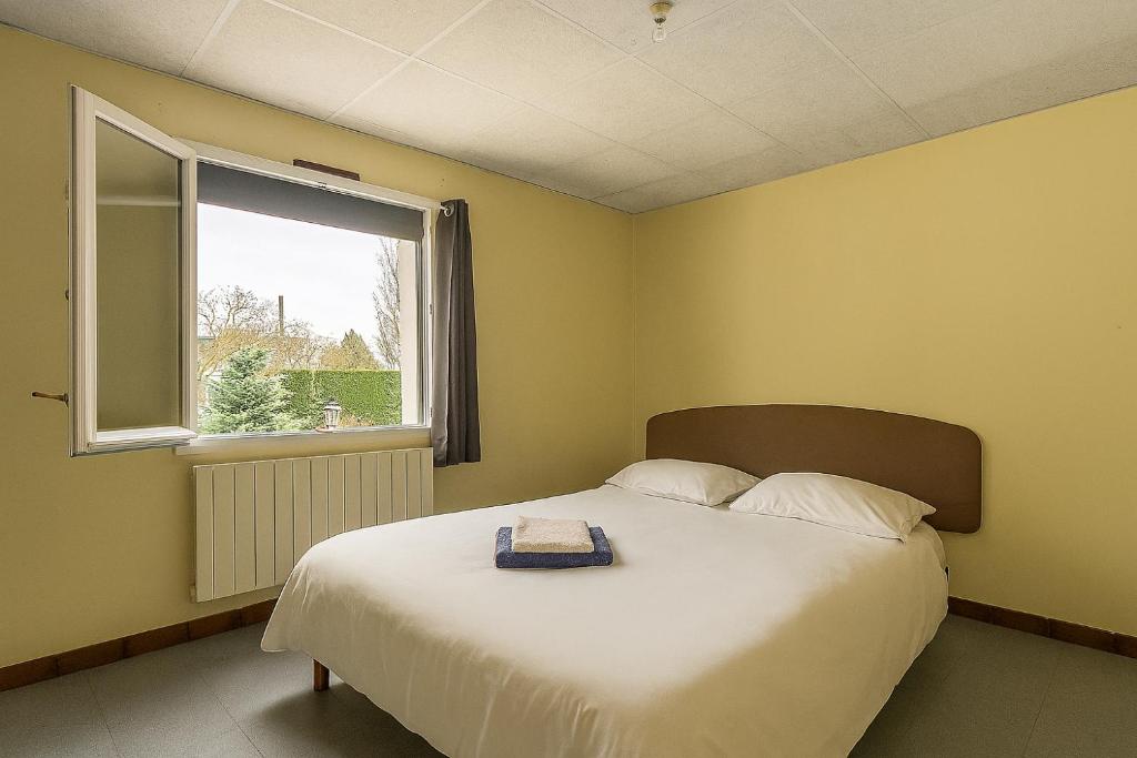 a bedroom with a large bed and a window at L'Arbre de Vie in Montmarault