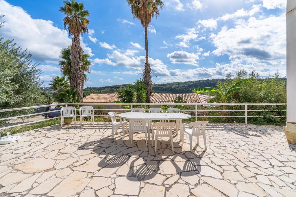 a patio with a table and chairs and palm trees at Fiumara Val Di Noto Country Rooms in Noto