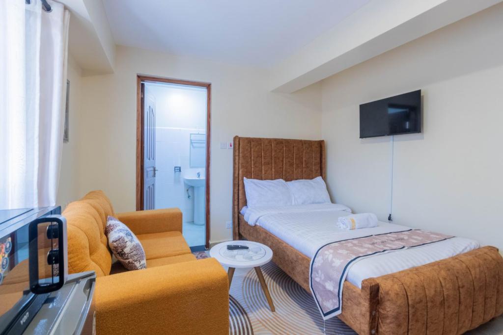 Un dormitorio con una cama, un sofá y un televisor. en Hazel Studio with free WI-FI, en Nanyuki