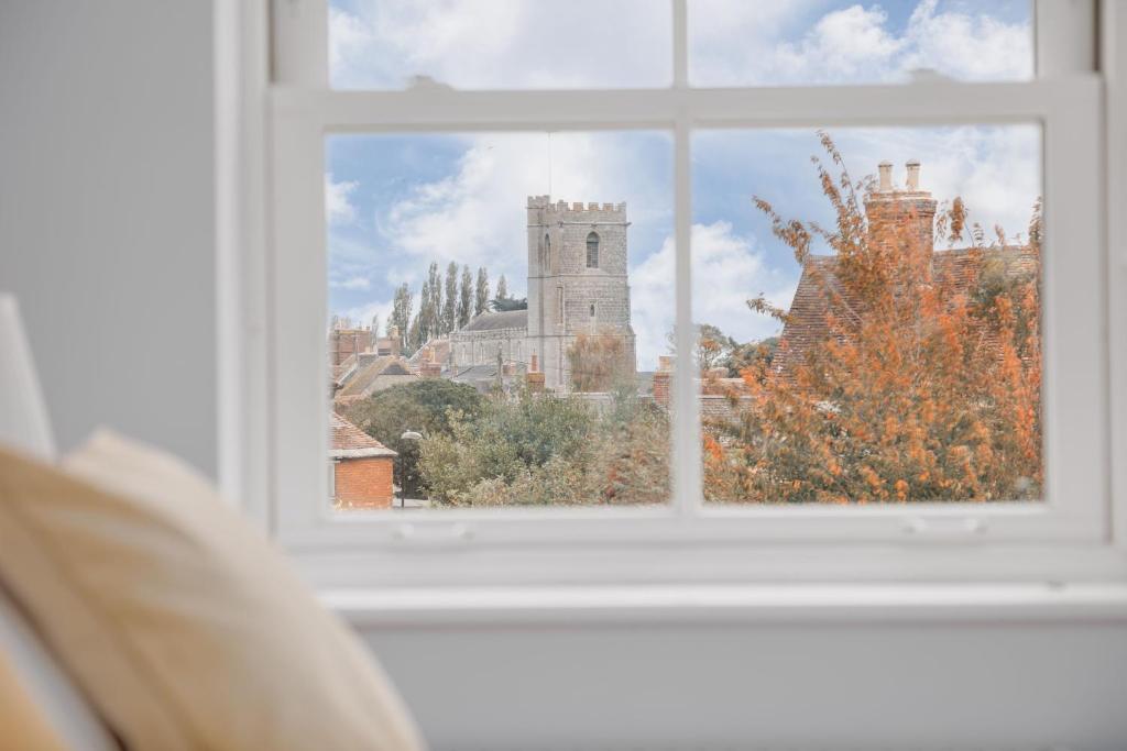 a window with a view of a tower and buildings at Saxon Mews in Wareham