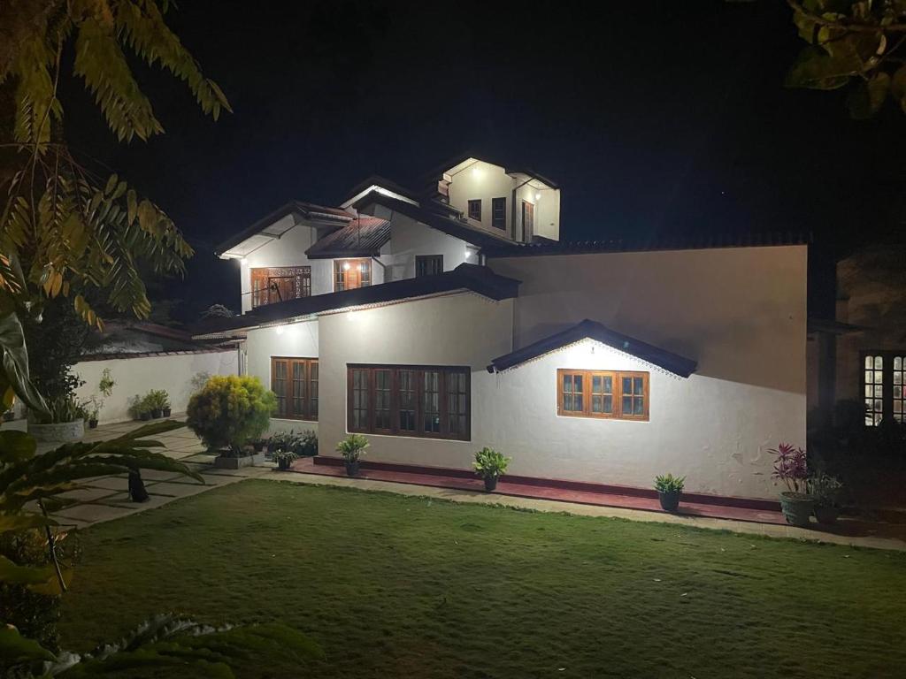 a large white house with a yard at night at Penthouse Bandarawela in Bandarawela