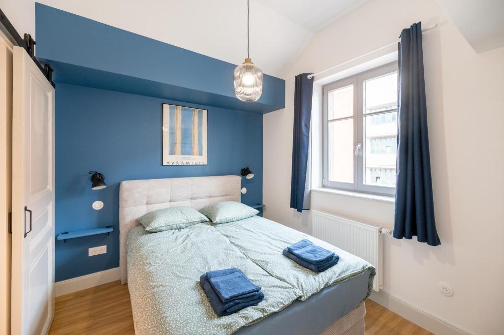 - une chambre avec des murs bleus et un lit avec 2 serviettes dans l'établissement Chez Lilly - Neuf - Haut de Gamme - Tram - Proche centre-ville - Tout confort, à Strasbourg