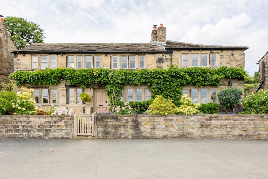 une ancienne maison en briques avec un mur en pierre dans l'établissement Woodlea Cottage, à Moffat