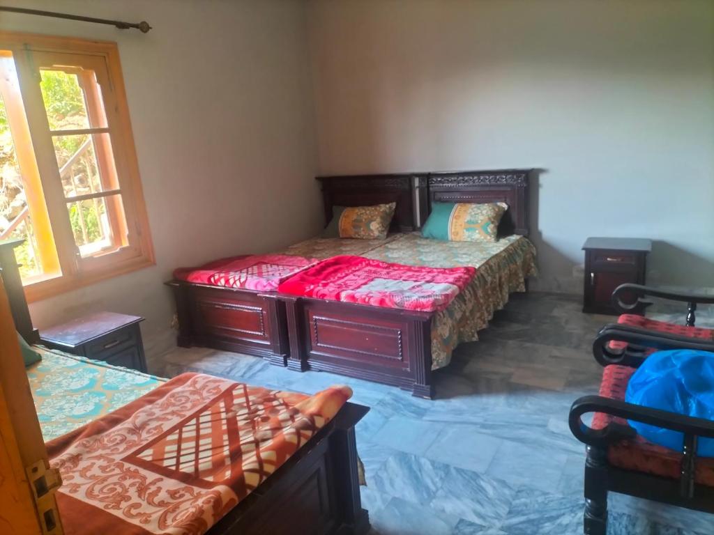 une chambre avec deux lits et une fenêtre dans l'établissement Ad cottage, à Nathia Gali