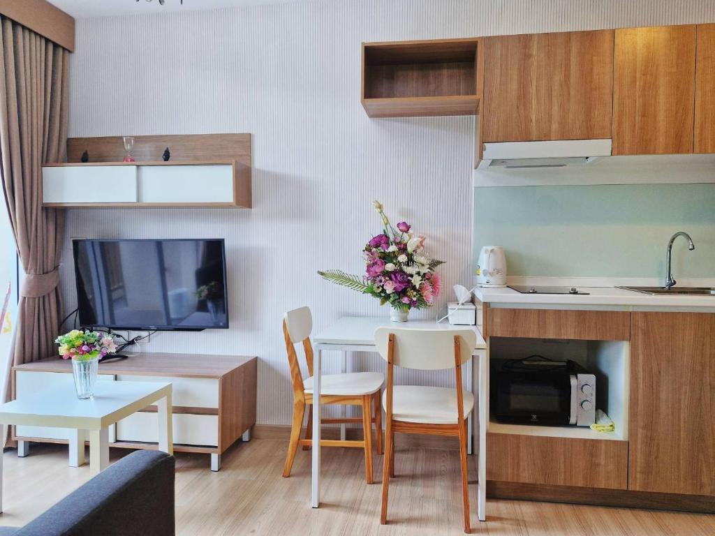 a living room with a kitchen and a table with chairs at Baan Khaoyai by Chateau in Ban Tha Maprang