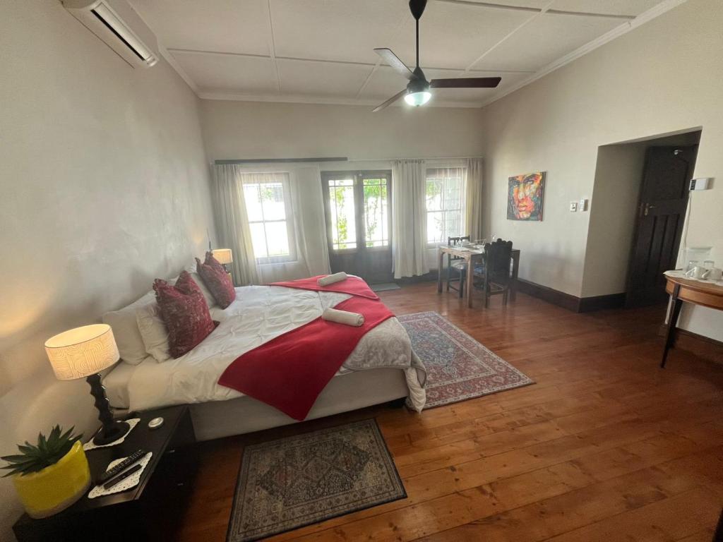 a bedroom with a large bed with a red blanket at Toni's Cottage in Graaff-Reinet